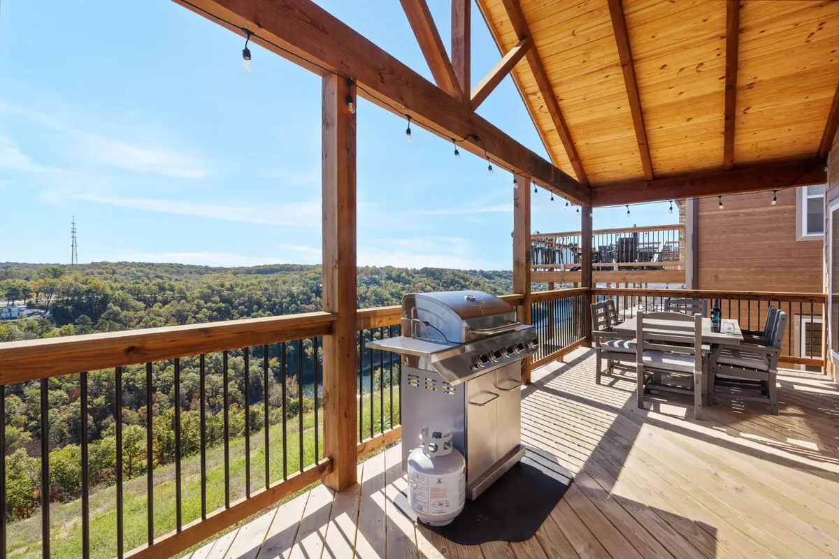 An exterior perspective showing a deck with a grill and dining table overlooking a natural landscape. This is the quintessential spot for al fresco meals, evening barbecues, and outdoor bonding after a day of adventure.