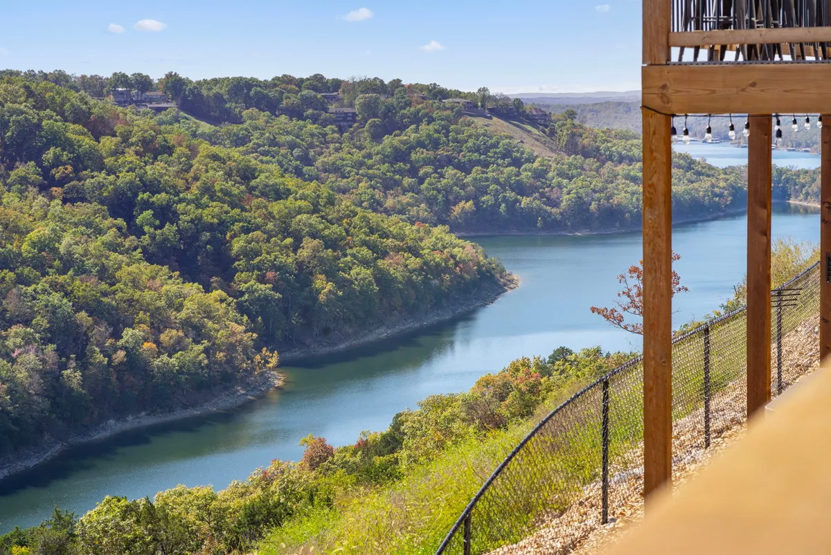 A sweeping view of a winding river bordered by lush greenery, with hills in the background. The scene is tranquil and inviting, suggesting the natural beauty of the area and opportunities for outdoor exploration like hiking or lakeside walks.