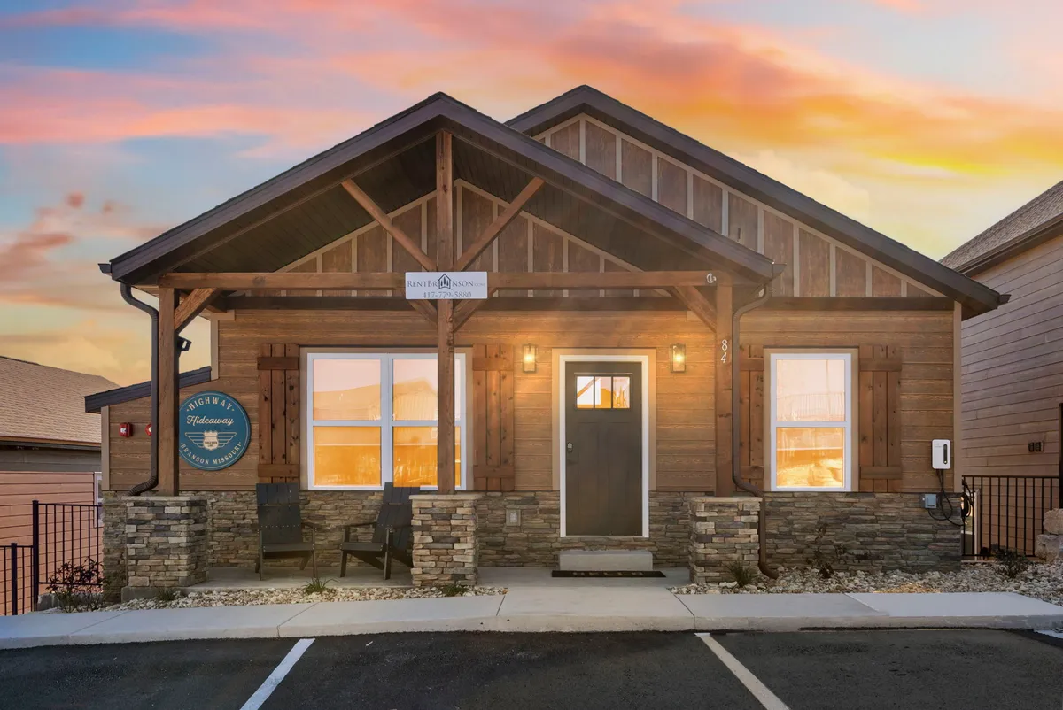 A close-up view of the wooden front door, stone foundation, and front porch seating. The outdoor area suggests relaxation and a welcoming atmosphere—a place to recharge both literally and figuratively.