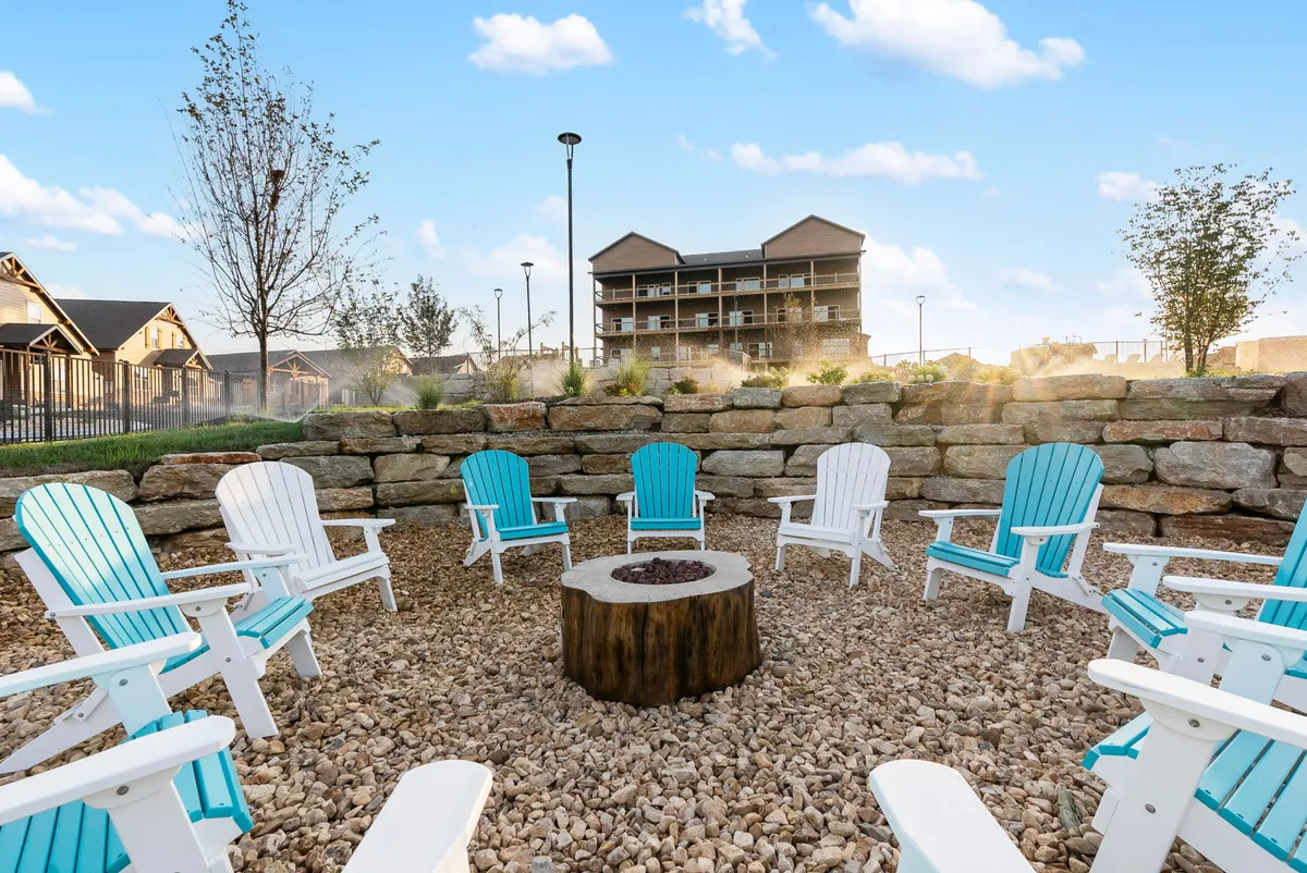 A cozy, communal fire pit area surrounded by Adirondack chairs and a rock wall, inviting groups to gather, socialize, and share stories as the sun sets. The atmosphere is warm, communal, and ideal for ending a day of exploration.